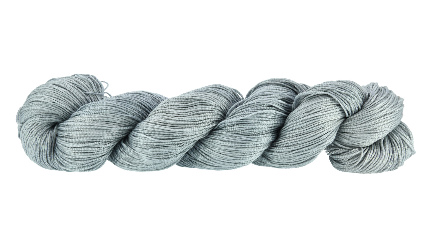 Barn Yarn Hand-dyed fingering weight yarn in colorway I Slate a Dragon! — 100% recycled cotton in a soft light gray tone, twisted into a hank to highlight its smooth 4-ply construction and subtle luster.