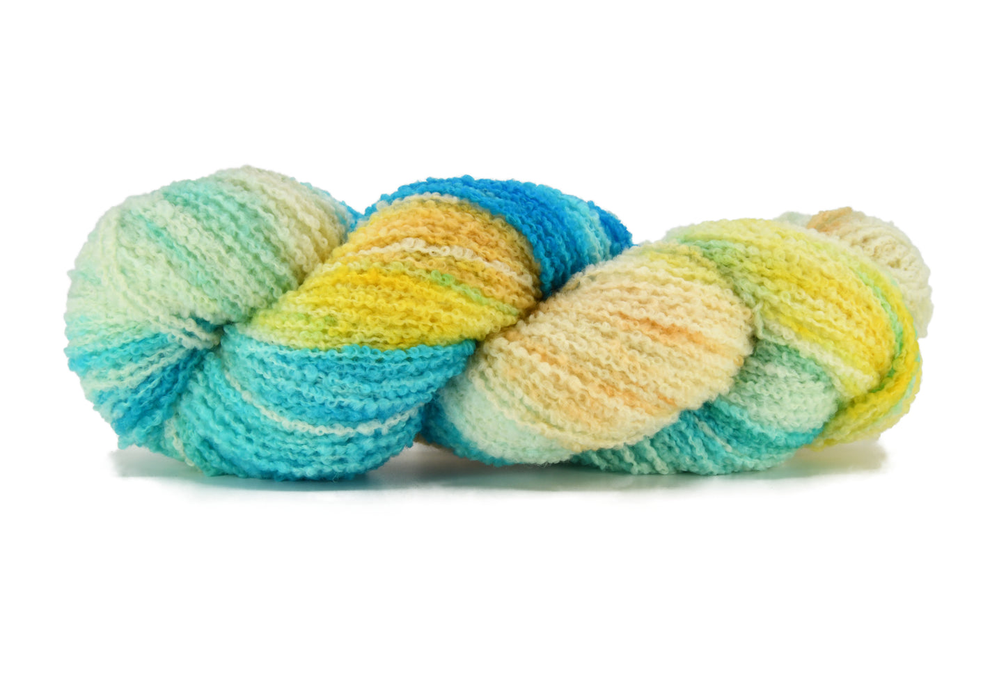 A twisted skein of Barn Yarn hand-dyed boucle DK weight yarn in colorway Down by the Seaside with breezy blues, sandy neutrals, and sea-glass greens, perfect knitting and crochet.
