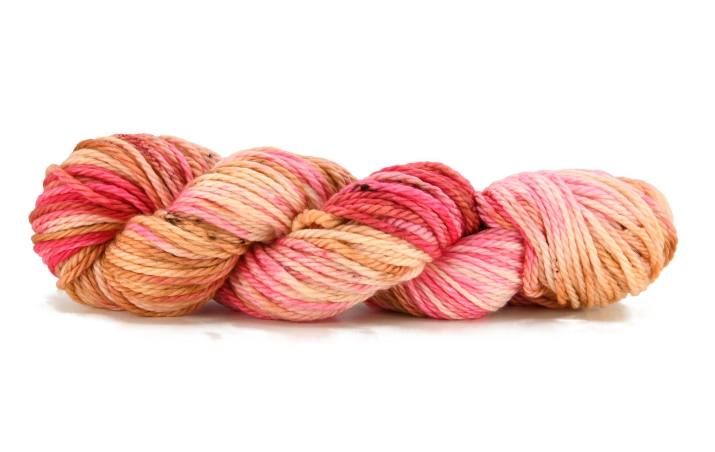 A twisted skein of Barn Yarn hand-dyed bulky weight yarn in colorway Poolside Popsicle featuring bright strawberry pink, vanilla and chocolate sprinkles, perfect for knitting and crochet projects.