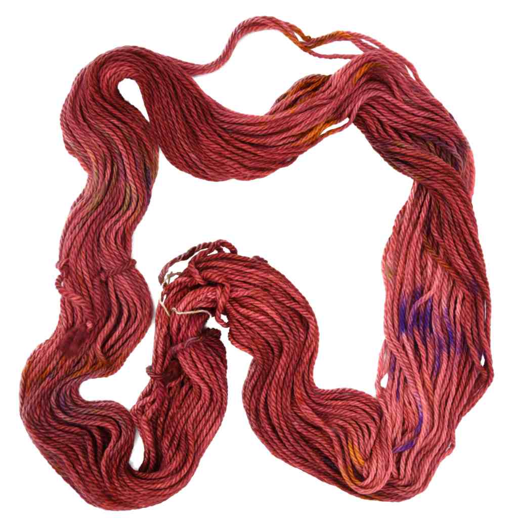 An unfolded skein of Barn Yarn hand-dyed bulky weight yarn in colorway Smitten - reddish cinnamon with flecks of purple, orange, brown and red undertones, perfect for cozy knitting and crochet projects.