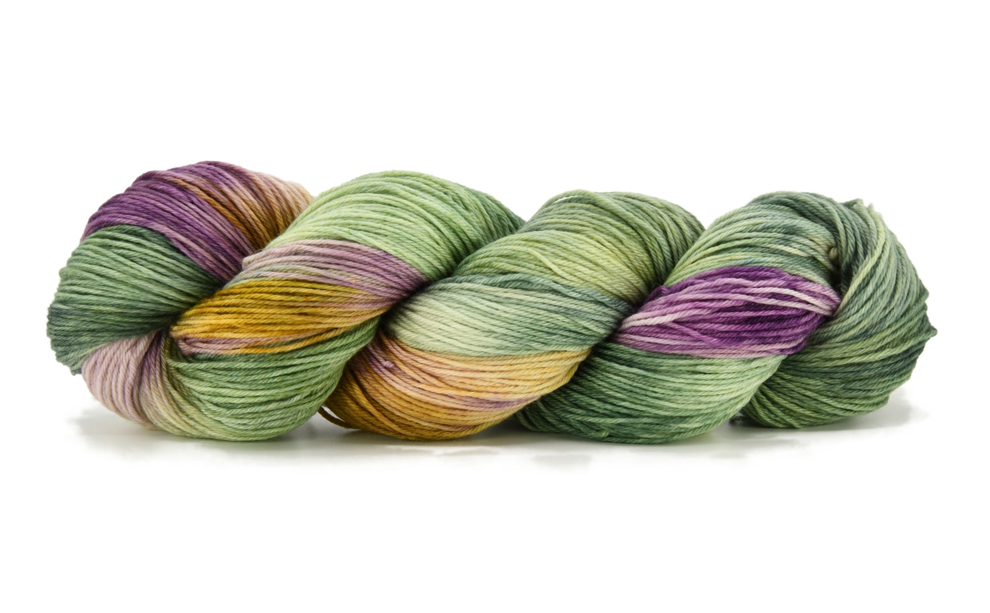 A twisted skein of Barn Yarn hand-dyed merino-cashmere-nylon yarn in colorway Pistachio, soft green shades with creamy toffee and purple undertones, perfect for fresh and playful knitting and crochet projects.