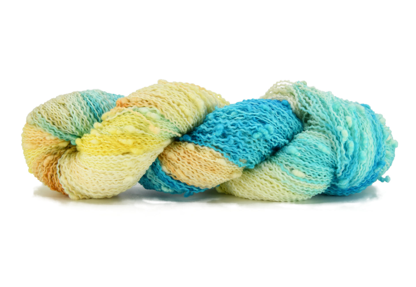 A twisted skein of Barn Yarn hand-dyed slub yarn in colorway Down by the Seaside with breezy blues, sandy neutrals, and sea-glass greens, perfect knitting and crochet.
