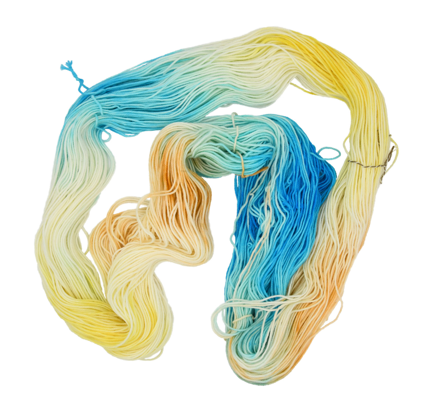 An unfolded skein of Barn Yarn hand-dyed sport weight yarn in colorway Down by the Seaside with breezy blues, sandy neutrals, and sea-glass greens, perfect knitting and crochet.