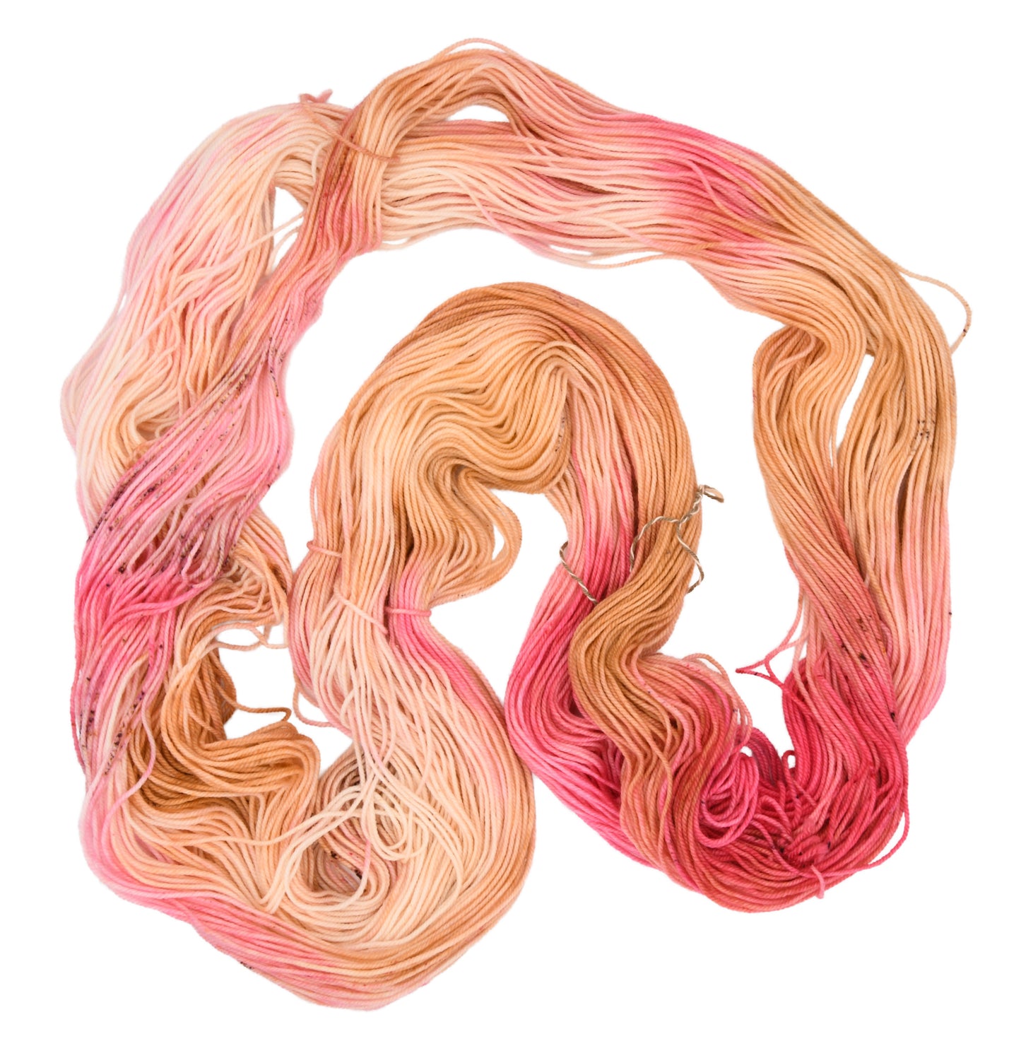An unfolded skein of Barn Yarn hand-dyed sport weight yarn in colorway Poolside Popsicle featuring bright strawberry pink, vanilla and chocolate sprinkles, perfect for knitting and crochet projects.