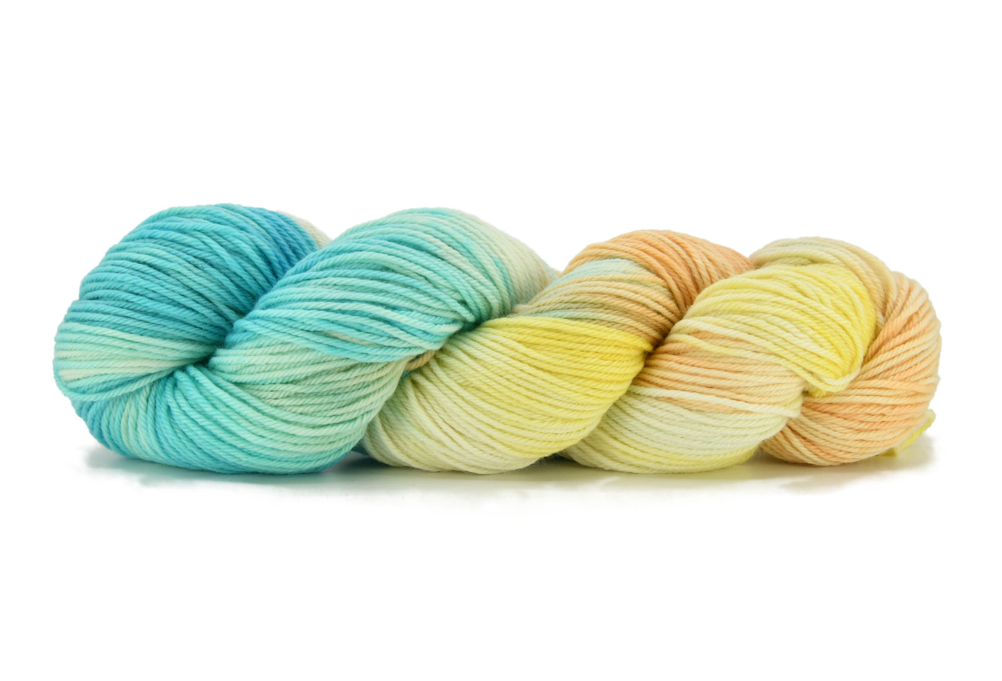 A twisted skein of Barn Yarn hand-dyed worsted weight yarn in colorway Down by the Seaside with breezy blues, sandy neutrals, and sea-glass greens, perfect knitting and crochet.