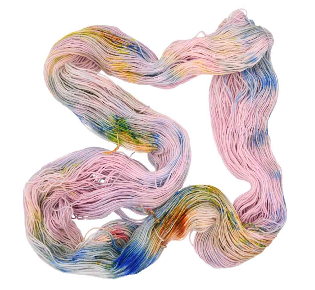 An unfolded skein of Barn Yarn Snowflake-2 fingering weight hand-dyed yarn in light pink and blue with orange, yellow, and green speckles, made sustainably from recycled dye.