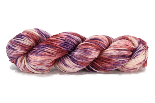 A twisted skein of Barn Yarn hand-dyed worsted weight yarn in colorway Very Berry - saturated berry tones of pink, purple and plum, perfect for cozy knitting and crochet projects.