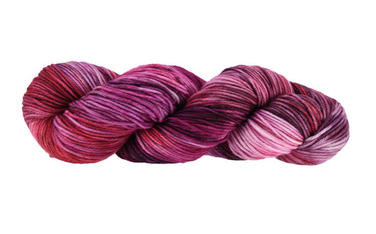 A twisted skein of Barn Yarn hand-dyed DK weight yarn in colorway Feelin’ Berry Glam! featuring vibrant berry tones with purple, pink, and jewel-like shades, perfect for stylish knitting and crochet projects.