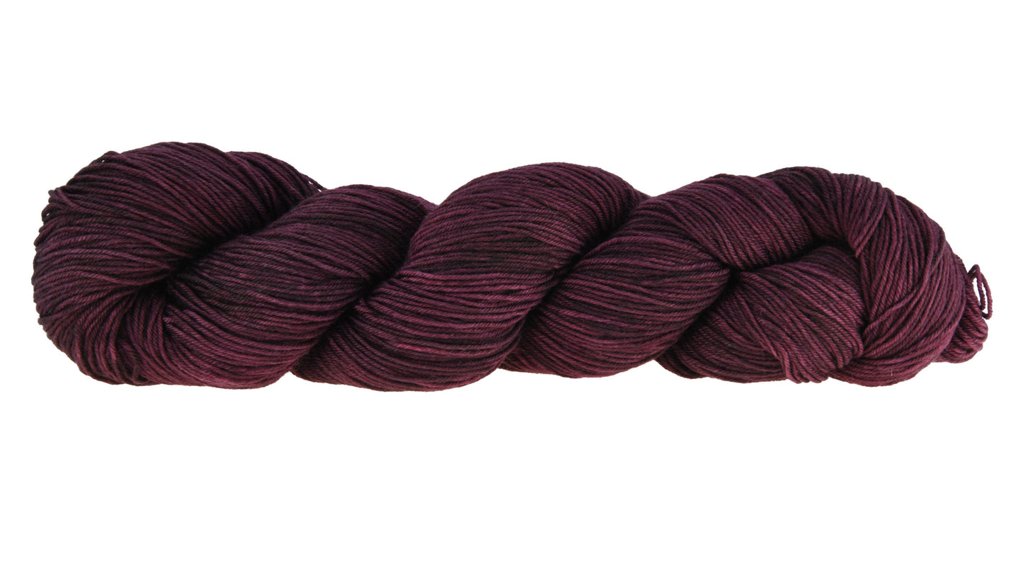 A twisted skein of Barn Yarn hand-dyed fingering weight yarn in colorway Plum; a rich, deep purple shade, perfect for sophisticated knitting and crochet projects.