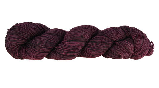 A twisted skein of Barn Yarn hand-dyed fingering weight yarn in colorway Plum; a rich, deep purple shade, perfect for sophisticated knitting and crochet projects.
