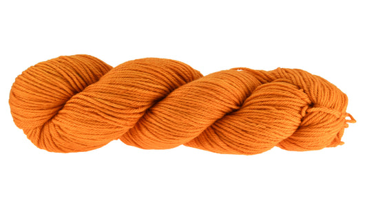 A twisted skein of Barn Yarn worsted hand-dyed yarn in colorway Pumpkin Orange in a bold, glowing orange shade, perfect for knitting and crochet projects with autumn warmth.