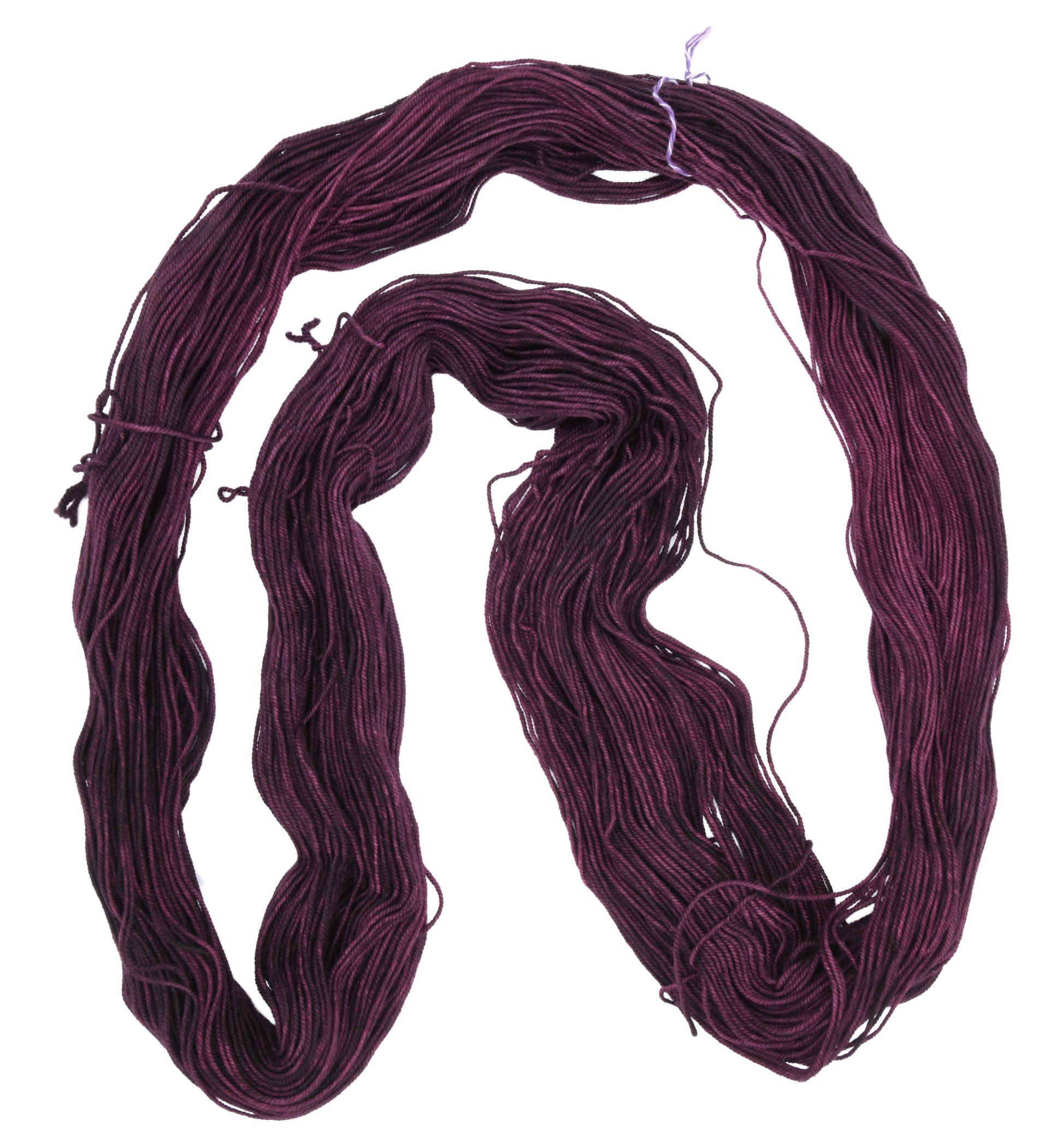 an unfolded skein of Barn Yarn hand-dyed sport weight yarn in colorway Plum; a rich, deep purple shade, perfect for sophisticated knitting and crochet projects.