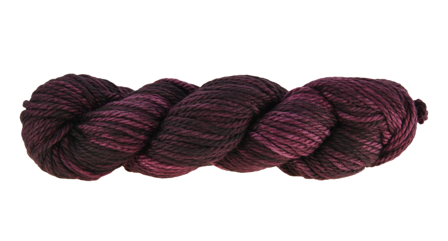 A twisted skein of Barn Yarn hand-dyed bulky weight yarn in colorway Plum; a rich, deep purple shade, perfect for sophisticated knitting and crochet projects.