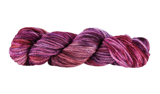 A twisted skein of Barn Yarn hand-dyed bulky weight yarn in colorway Feelin’ Berry Glam! featuring vibrant berry tones with purple, pink, and jewel-like shades, perfect for stylish knitting and crochet projects.