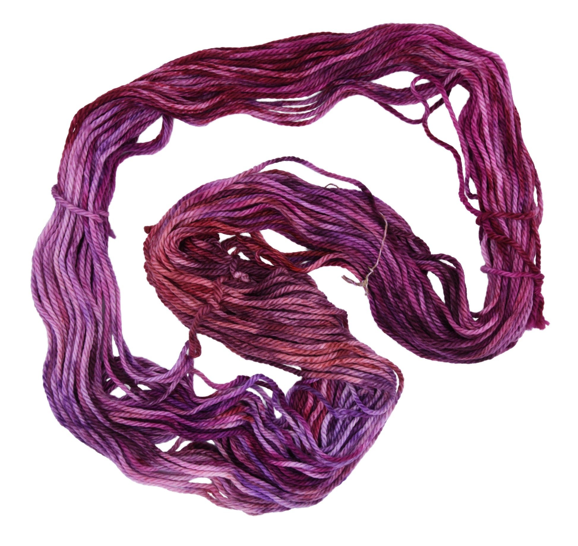 An unfolded skein of Barn Yarn hand-dyed bulky weight yarn in colorway Feelin’ Berry Glam! featuring vibrant berry tones with purple, pink, and jewel-like shades, perfect for stylish knitting and crochet projects.
