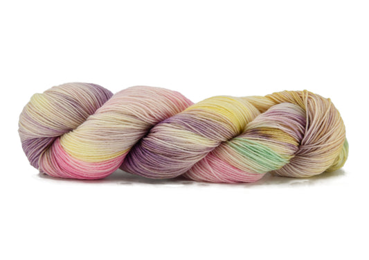 A twisted skein of Barn Yarn hand-dyed fingering weight yarn Bubble Bath, in soft blush pinks, airy whites, and lavender hints, perfect for delicate knitting and crochet projects.