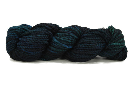 A twisted skein of Barn Yarn hand-dyed bulky weight yarn in colorway Raven -deep blue and black, perfect for bold, moody knitting and crochet projects.
