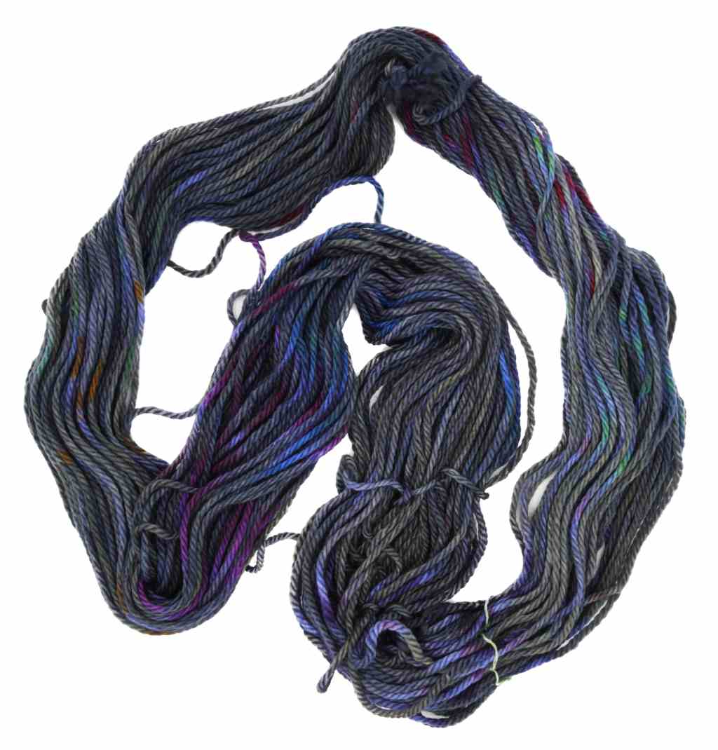 An unfolded skein of Barn Yarn hand-dyed bulky weight yarn in colorway Hallucination - deep bluish purple with undertones of magenta, gray, rust, and blue, ideal for knitting and crochet.