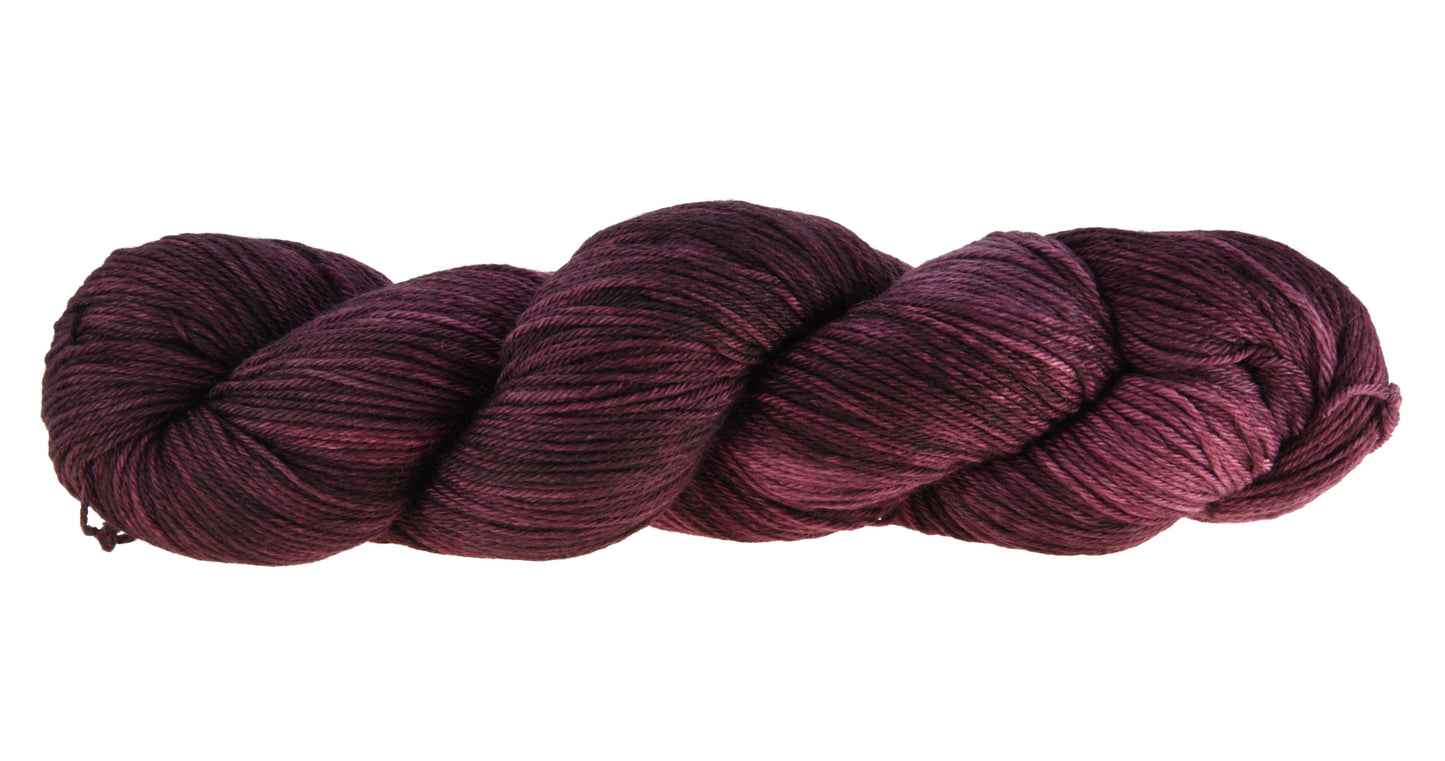 A twisted skein of Barn Yarn hand-dyed merino-cashmere-nyon blend yarn in colorway Plum; a rich, deep purple shade, perfect for sophisticated knitting and crochet projects.