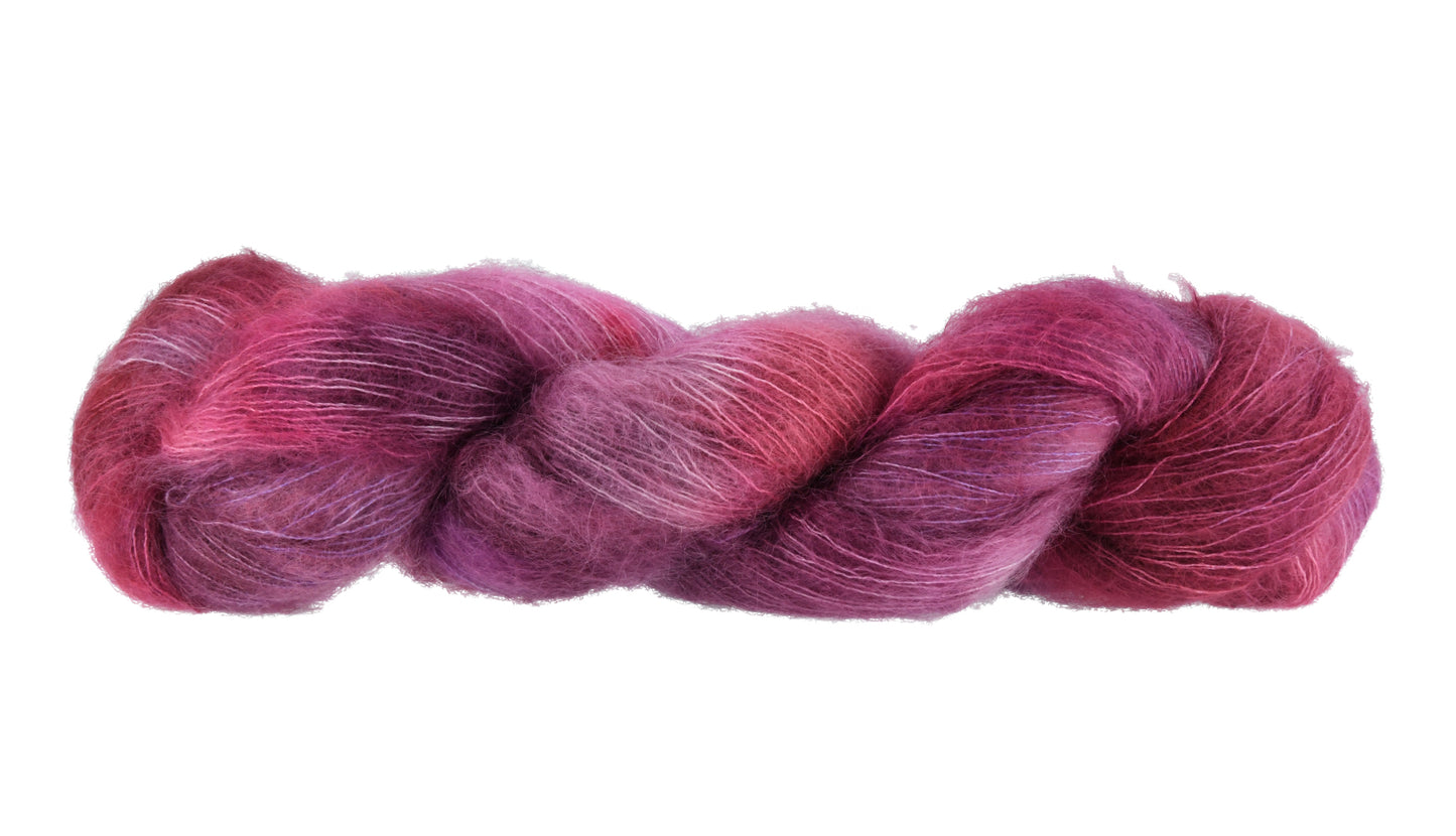 A twisted skein of Barn Yarn hand-dyed mohair yarn in colorway Feelin’ Berry Glam! featuring vibrant berry tones with purple, pink, and jewel-like shades, perfect for stylish knitting and crochet projects.