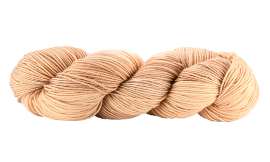 A twisted skein of Barn Yarn hand-dyed sport weight yarn in colorway Pink Sand, a soft blush pink with sandy undertones, perfect for knitting and crochet projects.