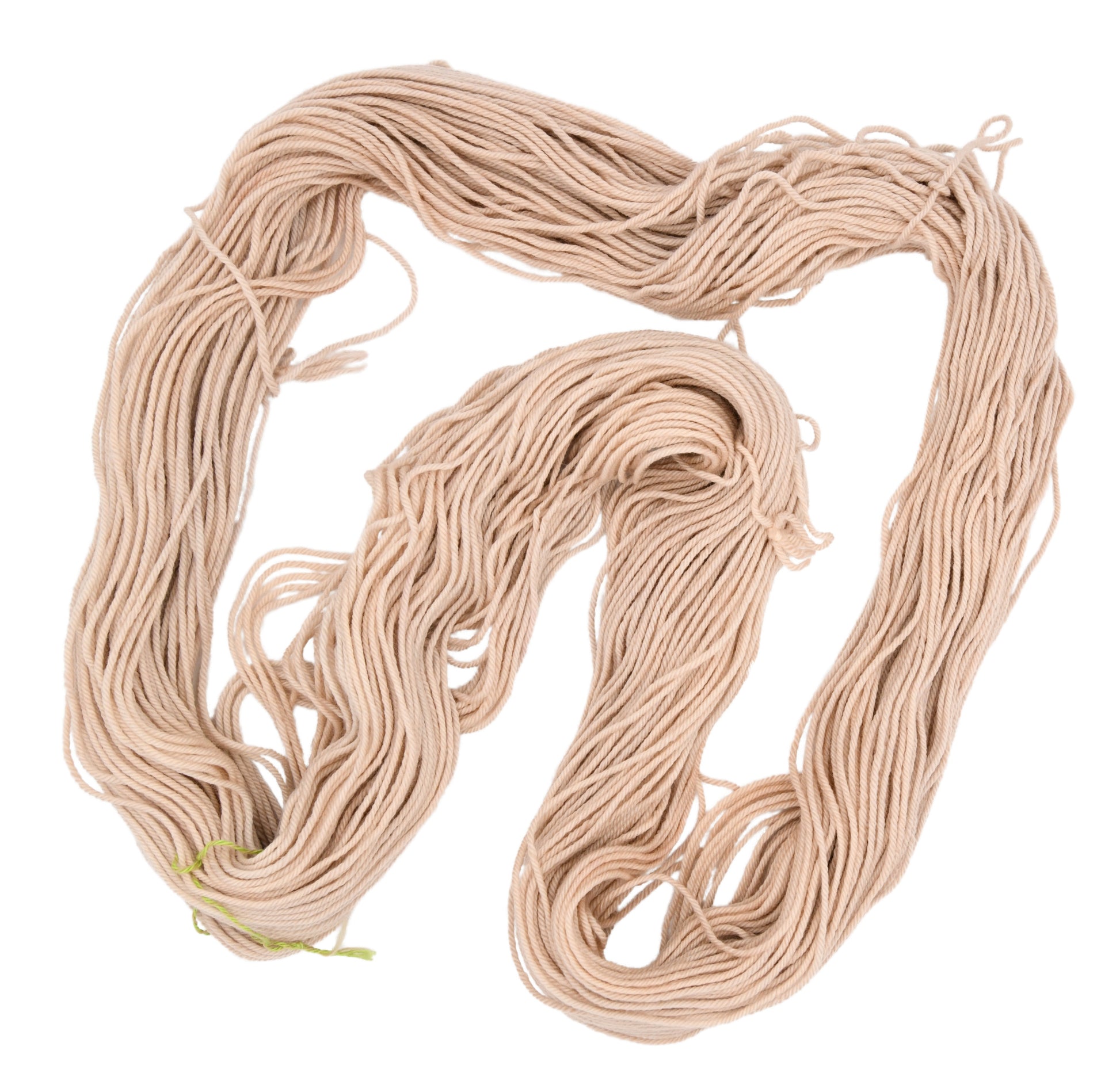 An unfodled skein of Barn Yarn hand-dyed worsted weight yarn in colorway Pink Sand, a soft blush pink with sandy undertones, perfect for knitting and crochet projects.