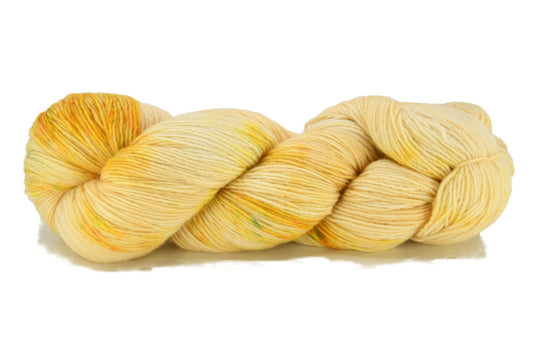 A twisted skein of barn yarn 1-ply hand-dyed fingering weight yarn in colorway Honeysuckle - soft shades yellow with golden undertones, perfect for elegant knitting or crochet projects.
