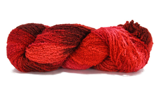 A twisted skein of Barn Yarn hand-dyed boucle DK in colorway Candy Apples - vivid red with highlights of maroon, perfect for textured knitting and crochet projects