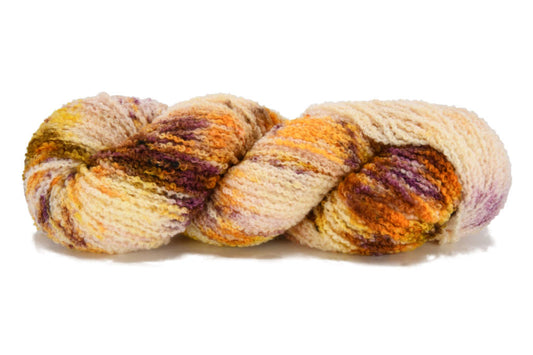 A twisted skein of Barn Yarn hand-dyed boucle DK yarn in colorway Harvest - golden amber and burnt orange with subtle speckles of brown and cream, perfect for textured knitting and crochet projects.