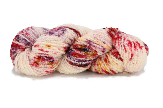 A twisted skein of Barn Yarn hand-dyed boucle DK weight yarn in colorway Sunny Orchard - bright red on cream with speckles of gold, plum, and black, perfect for textured knitting and crochet projects.