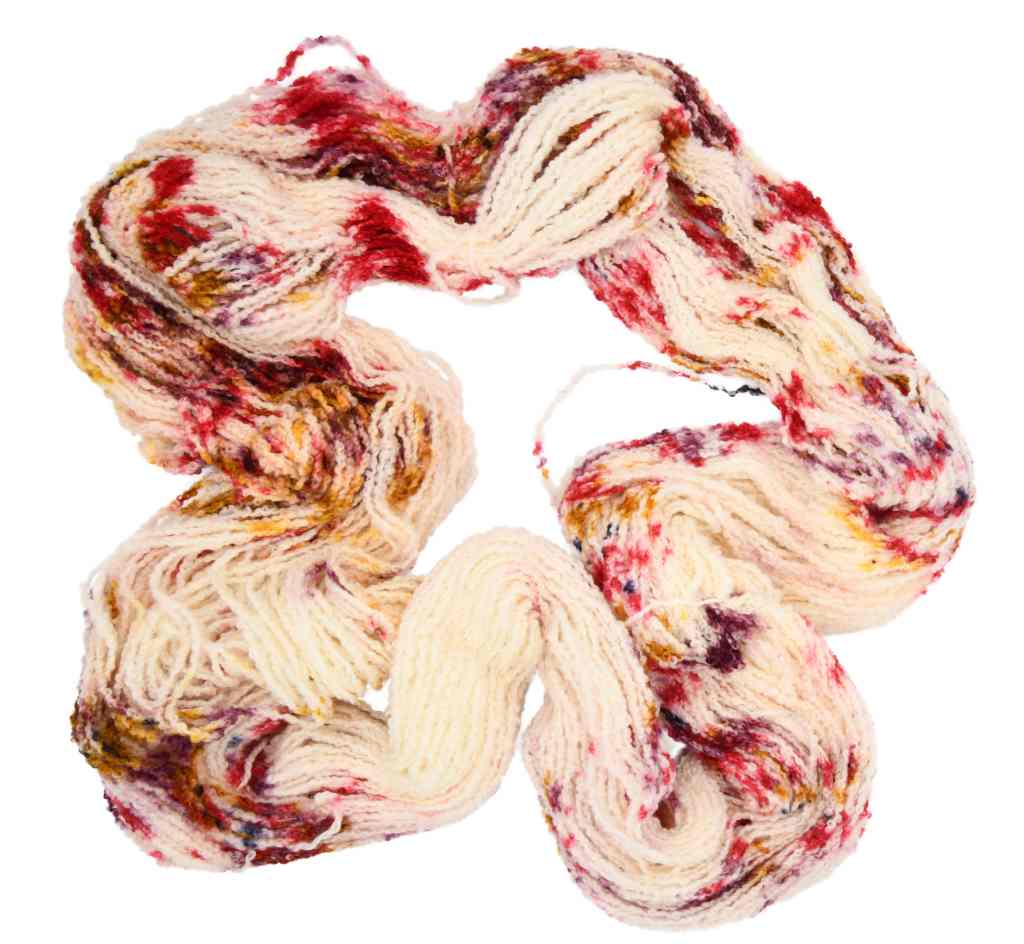 An unfolded skein of Barn Yarn hand-dyed boucle DK weight yarn in colorway Sunny Orchard - bright red on cream with speckles of gold, plum, and black, perfect for textured knitting and crochet projects.