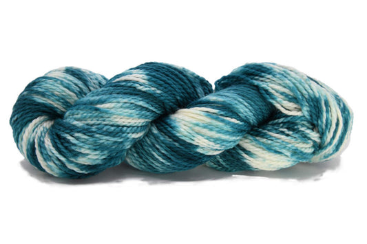 A twisted skein of Barn Yarn hand-dyed bulky weight yarn in colorway Verdigris - rich teal-green tones with cream, perfect for knitting and crochet projects.