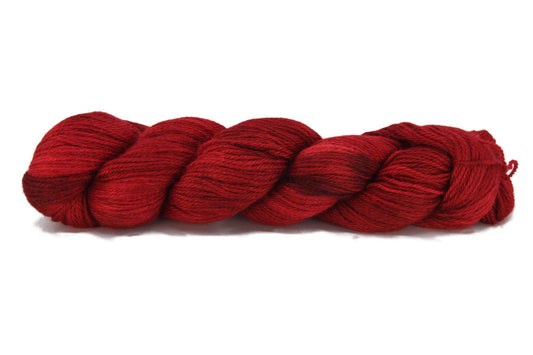 A twisted skein of Barn Yarn sport weight 100% alpaca yarn in colorway Holiday Mood - a rich tonal red, perfect for festive and elegant knitting or crochet projects.