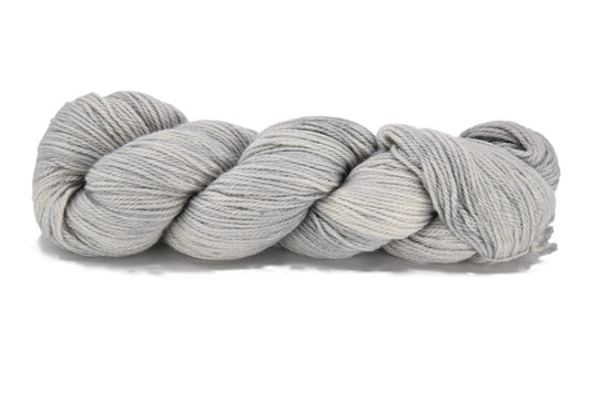 A twisted skein of Barn Yarn hand-dyed sport weight alpaca yarn in colorway Silver Bells -silvery-gray tones, perfect for soft and elegant knitting or crochet projects. 