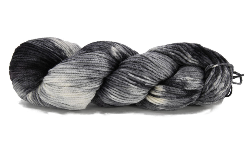 A twisted skein of Barn Yarn hand-dyed worsted weight yarn in Colorway Storm - black, gray, and cream, evoking the moody tones of a passing storm - perfect for knit and crochet projects