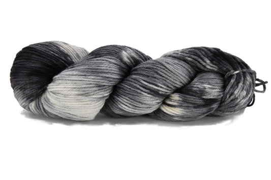 A twisted skein of Barn Yarn hand-dyed worsted weight yarn in Colorway Storm - black, gray, and cream, evoking the moody tones of a passing storm - perfect for knit and crochet projects