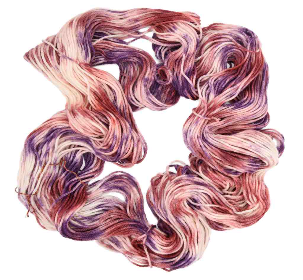 A twisted skein of Barn Yarn hand-dyed worsted weight yarn in colorway Very Berry - saturated berry tones of pink, purple and plum, perfect for cozy knitting and crochet projects.